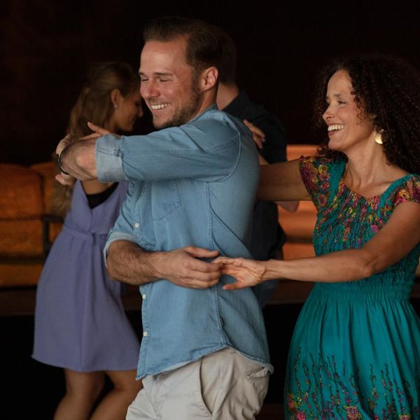 Ein Mann mit Jeanshemd und eine Frau im grünen Kleid tanzen zu Salsa auf der Tanzfläche