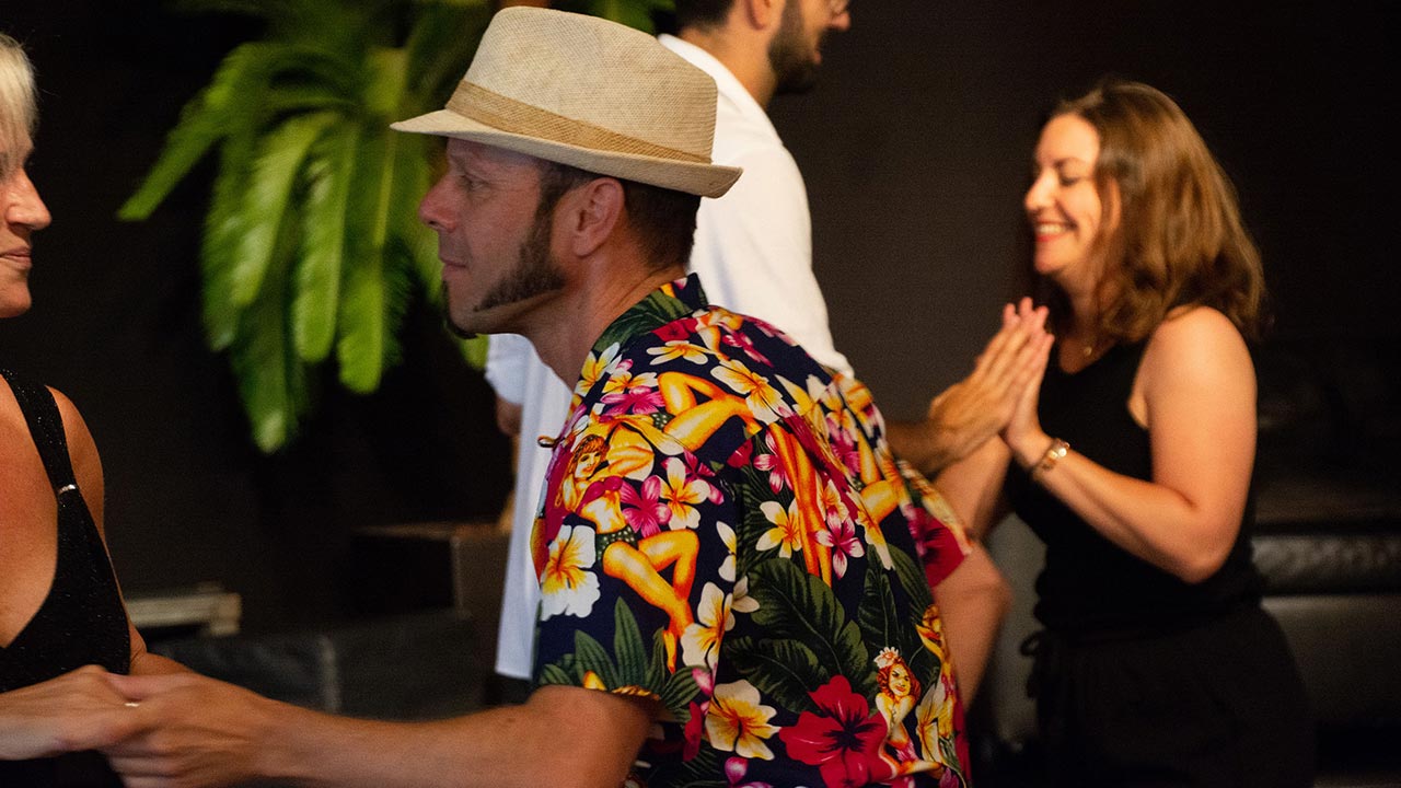 Tanzende Pärchen, Mann hat ein auffällig gemustertes Hemd und Hut an