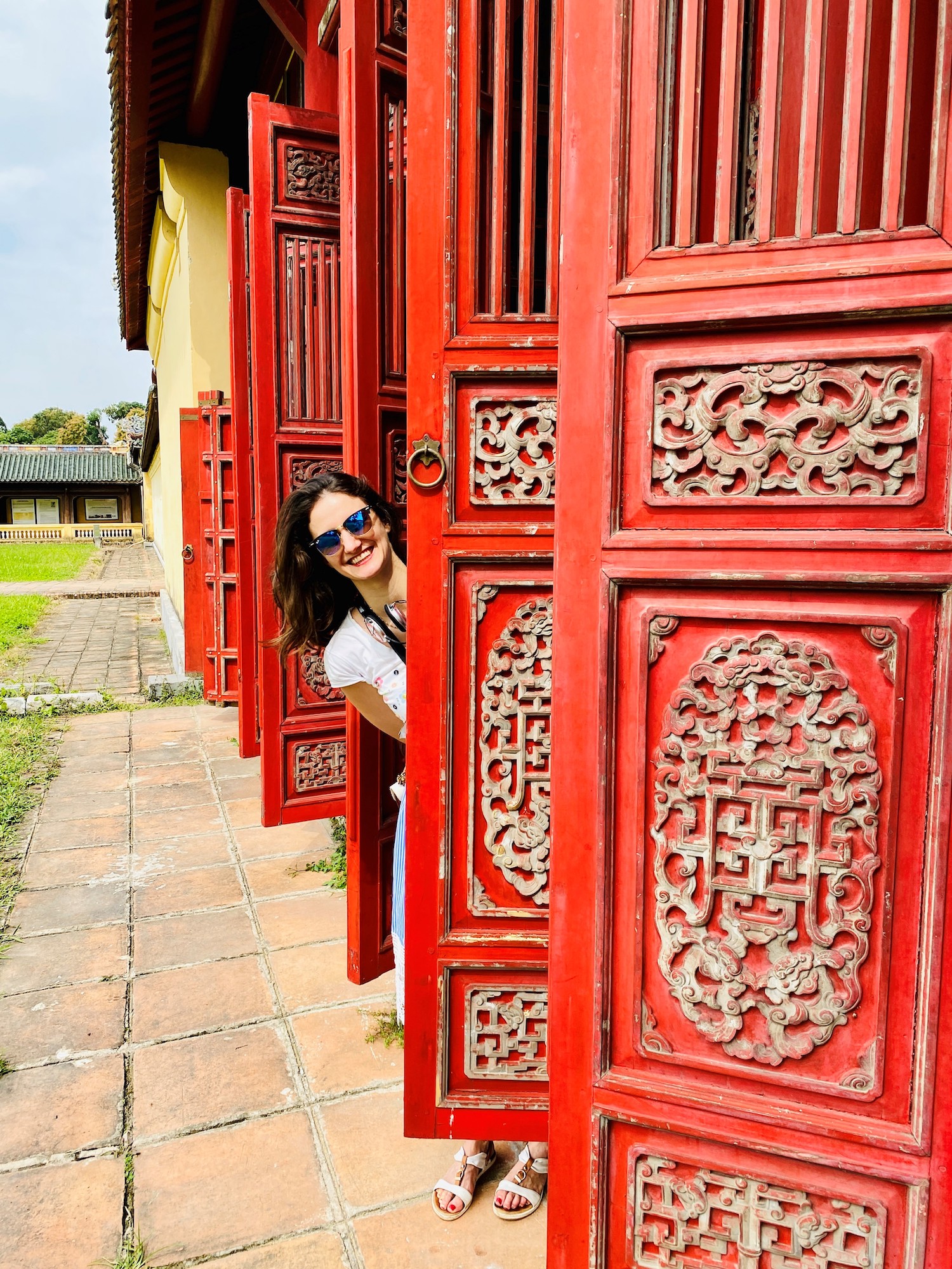 Frau schaut hinter einer roten asiatisch Türe hervor die zu einem Tempel gehört